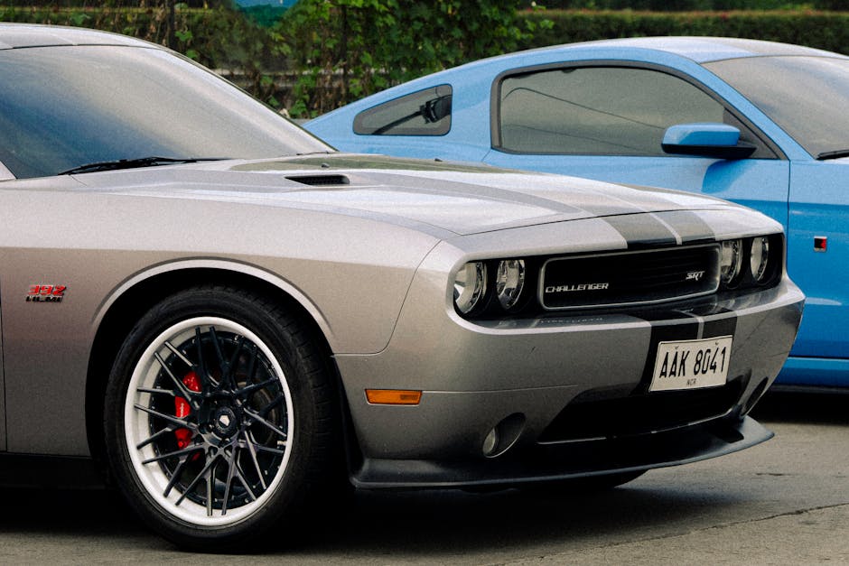 Silver Dodge Challenger and blue Ford Mustang parked outdoors, showcasing automotive design