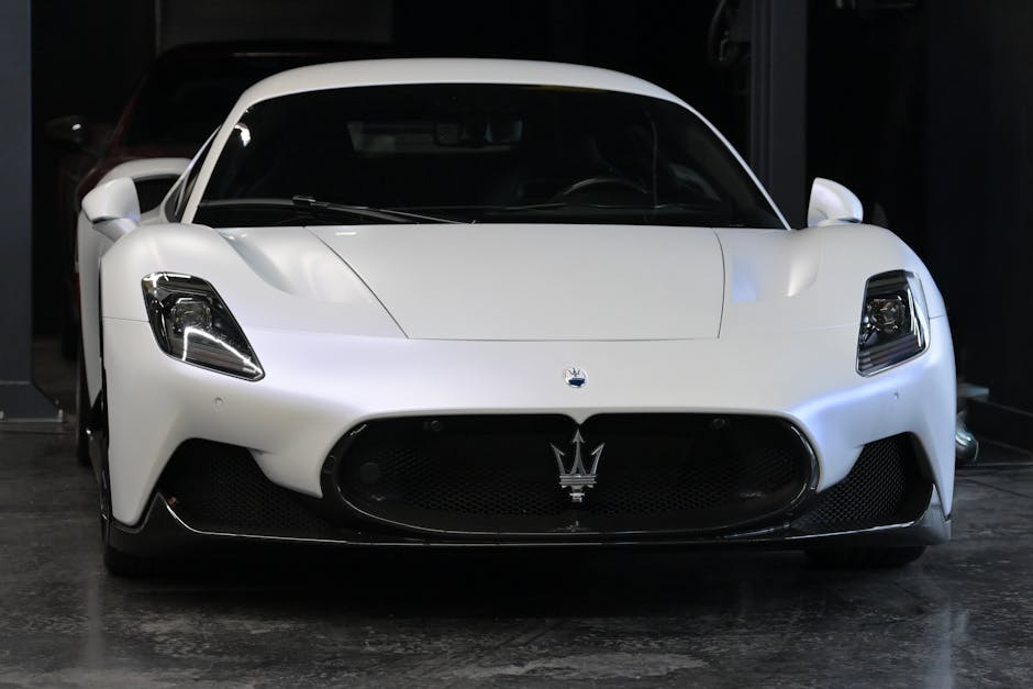 Front view of a striking white Maserati supercar showcased in a dimly lit garage setting