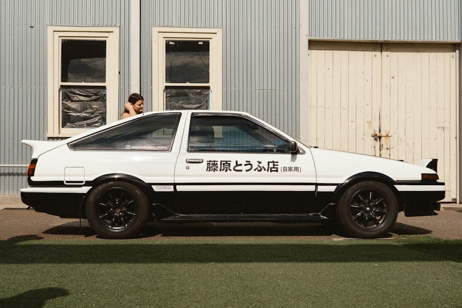 Side view of a classic Toyota AE86 with Japanese text in an urban environment